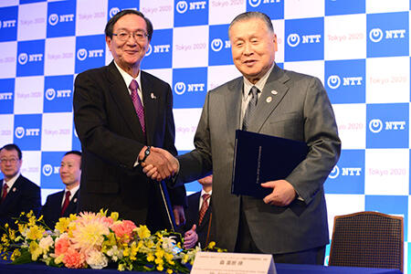 契約締結セレモニーで握手を交わす、東京2020組織委員会会長 森様（右）とNTT 鵜浦社長（左）