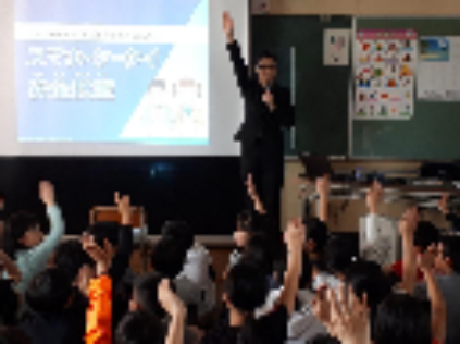 写真：スマホ・ケータイ安全教室で、小学生達が講師と一緒に手を挙げる様子