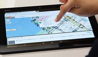 画像：バリアフリー情報収集技術「MaPiece®」を表示するタブレットと操作する手の写真。