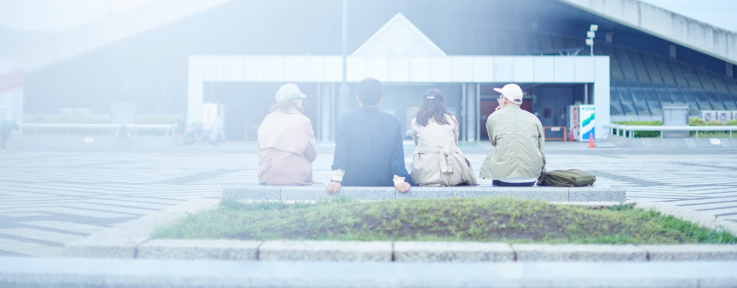 ベンチで会話をする若者たちの後ろ姿の写真
